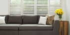 faux wood shutters in living room with grey sofa