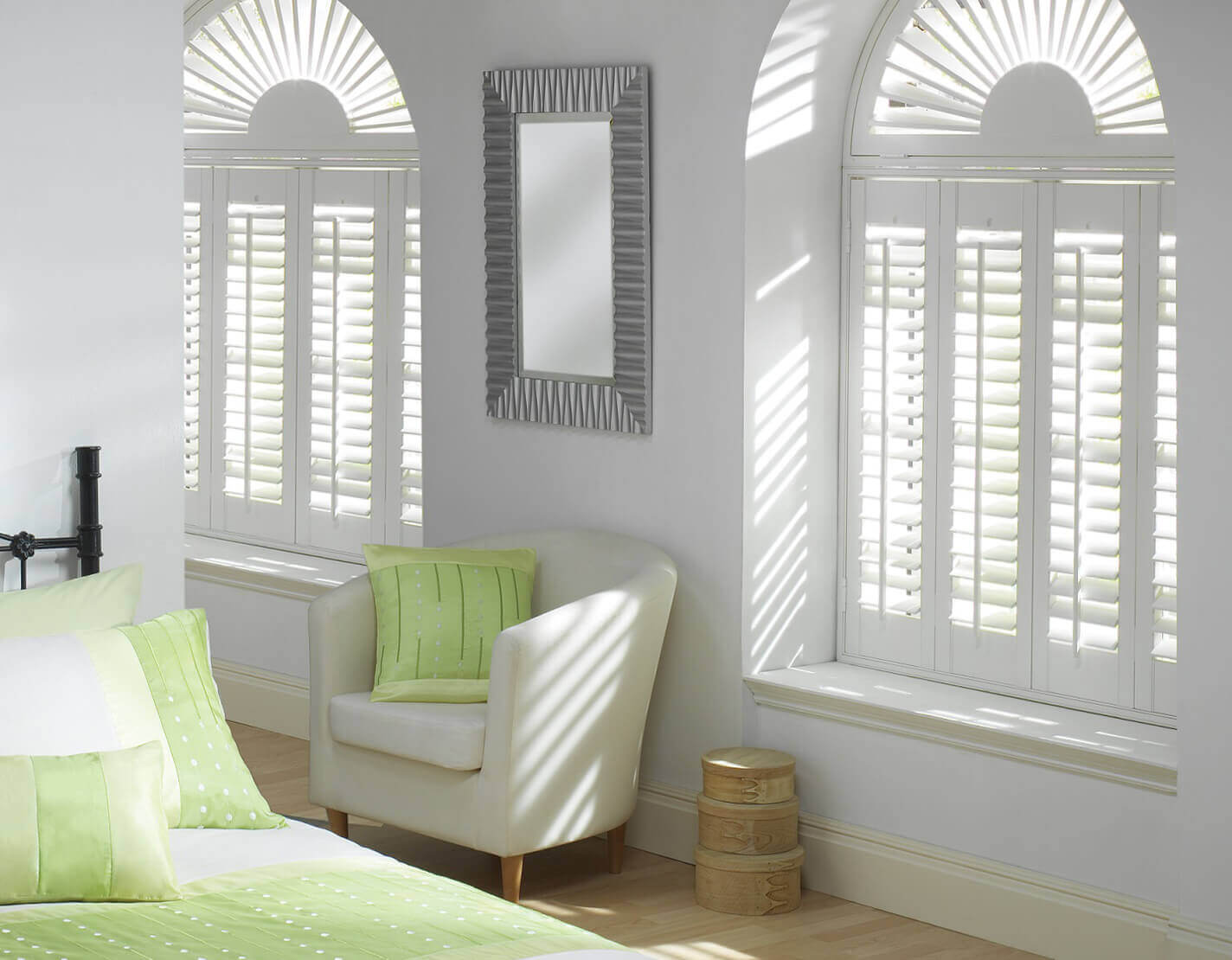 White wooden louvre shutters in white walled bedroom