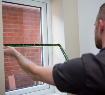 Professional blind fitter measuring a window for blinds