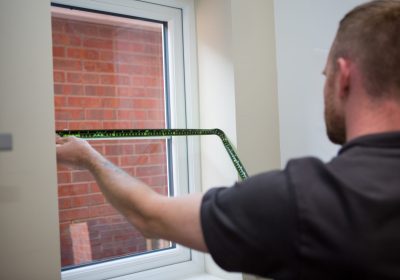 Professional blind fitter measuring a window for blinds