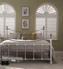 Arched window shutters in a bedroom