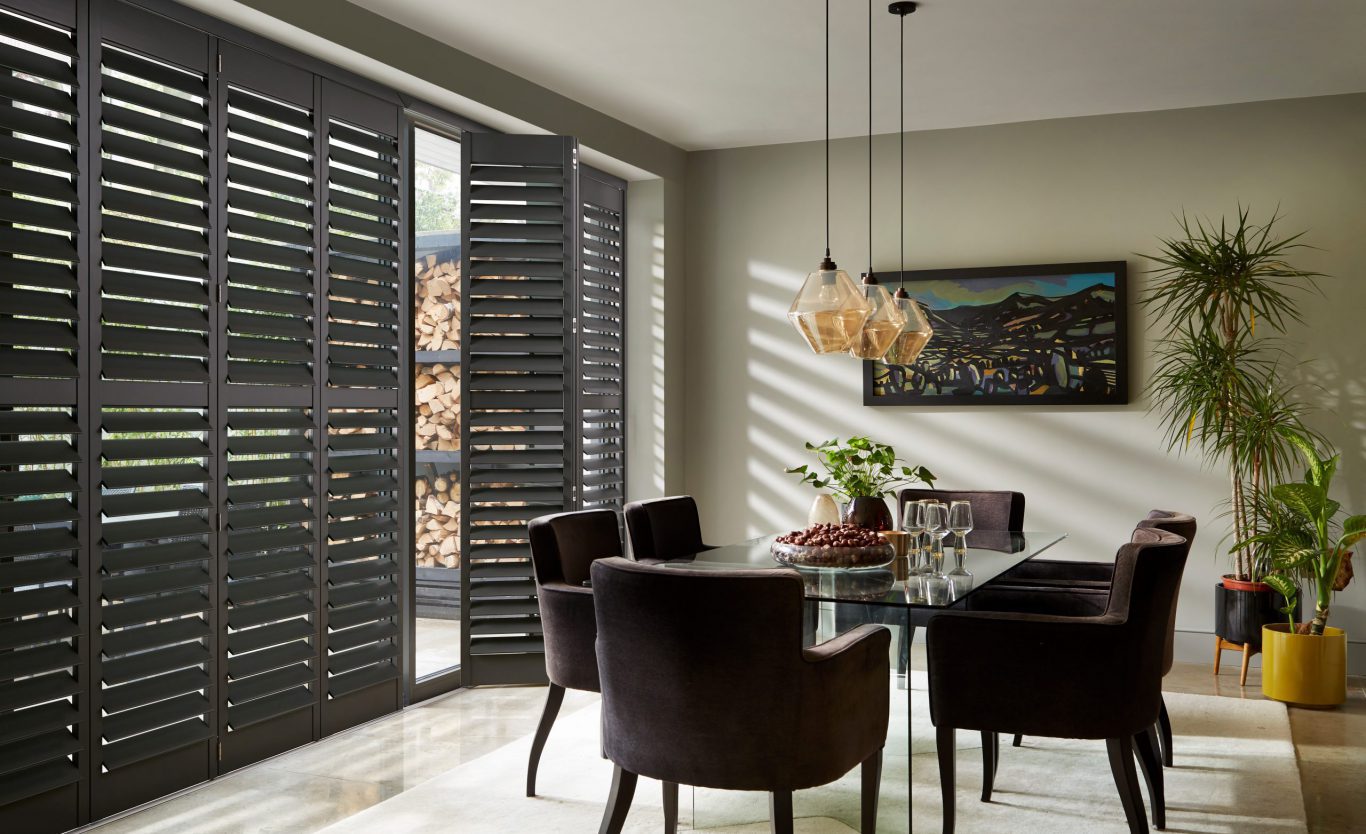 Grey full height wooden window shutters in dining room