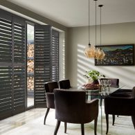 Grey full height wooden window shutters in dining room