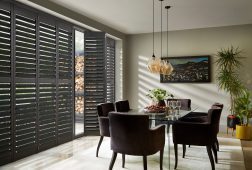 Grey full height wooden window shutters in dining room