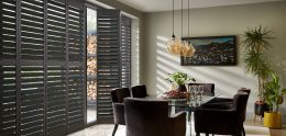 Grey full height wooden window shutters in dining room