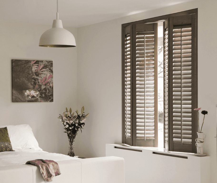 Full height grey wooden shutters in bedroom